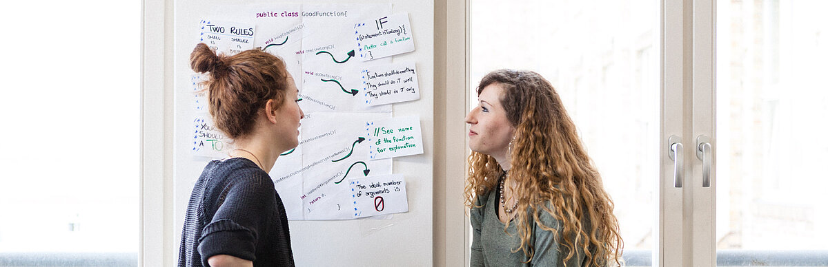 Zwei Studentinnen vor einer Mindmap an der Wand